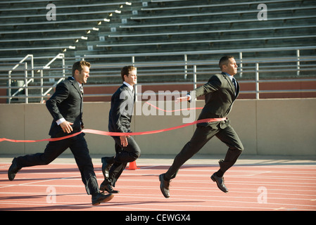 Imprenditore attraversando traguardo in gara Foto Stock