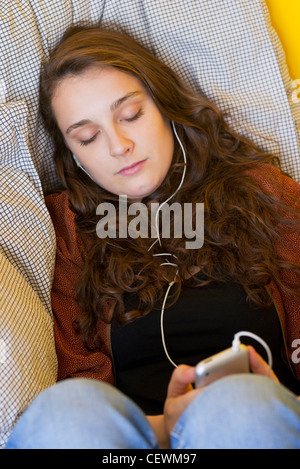Giovane donna ascoltando mp3 player con gli occhi chiusi Foto Stock
