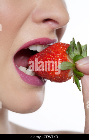 Femmina rosa da indossare lucidalabbra, mangiare una fragola, profilo a fotocamera Foto Stock