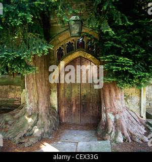 La porta nord di San Edwards chiesa con due antiche yew alberi su entrambi i lati. Foto Stock