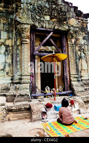 Donna che prega davanti a un santuario a Phnom Bakheng tempio in Siem Reap, Cambogia Foto Stock