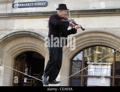 Un uomo suonare il violino saldi in un funambolico al di fuori di una banca locale a Oxford High Street. Inghilterra 2 Foto Stock