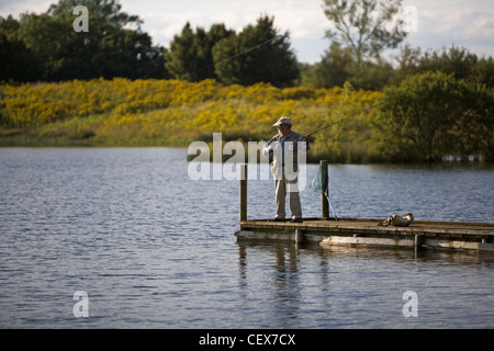 Un pescatore di Pesca a Mosca Report di Pesca dalla fine di un pontile su uno dei laghi che compongono il Cotswold Water Park. Foto Stock