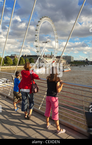 Una madre e i suoi figli godere la vista del London Eye dal Hungerford ponte sopra il fiume Tamigi Foto Stock