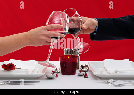 Foto di mani di una coppia di sposi tostare i loro bicchieri di vino in un ristorante tavola durante una cena romantica. Foto Stock