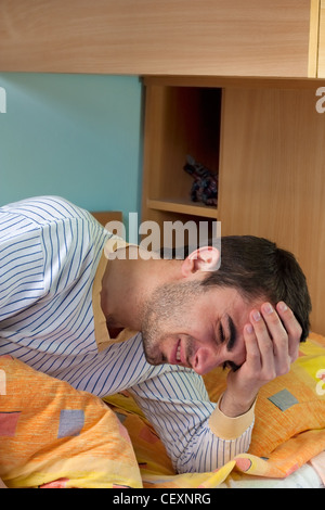 Giovane uomo svegliarsi e avere dei terribili mal di testa a causa dell'alcool stava bevendo la scorsa notte Foto Stock