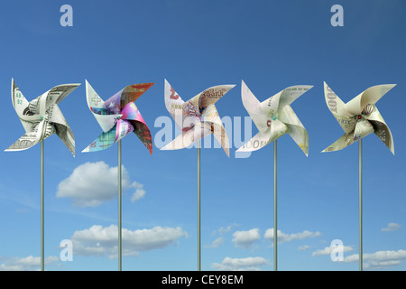 Mulini a vento giocattolo tagliati da cinque grandi mondo banconote in valuta oltre il cielo blu Foto Stock