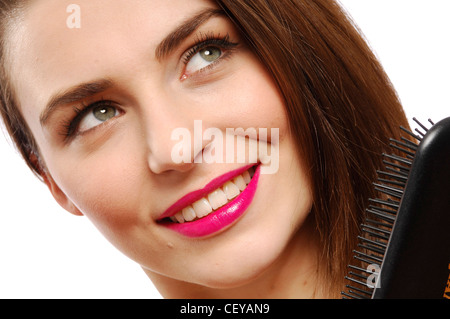 Close up femminile di indossare rosa luminoso lucidalabbra e nero Abito in raso spazzolatura lungo rettilineo bruna spazzola per capelli cercando di fino Foto Stock