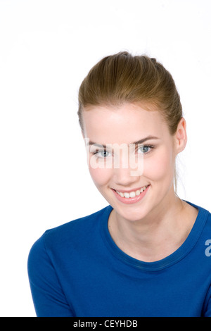 Femmina con capelli castani fuori la sua faccia, indossando una parte superiore blu, sorridente, guardando la fotocamera Foto Stock