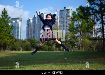 Schoolgirl jumping in un parco Foto Stock