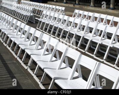 Righe di identiche sedi bianco sedie pieghevoli al sole sul lungomare di Eastbourne, East Sussex Foto Stock