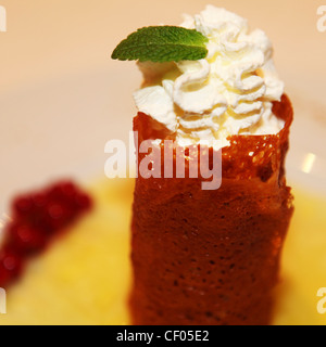 Una crema riempito di brandy snap condito con una foglia di menta. Foto Stock