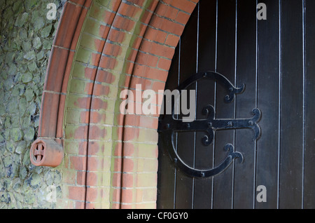 Decorativi in ferro battuto cerniera sulla porta esterna di una cappella nel cimitero di Wymondham, Norfolk, East Anglia, Inghilterra, Regno Unito. Foto Stock