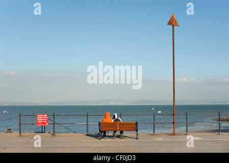 Un giovane che guarda al mare sul lungomare, Mumbles, Galles Foto Stock