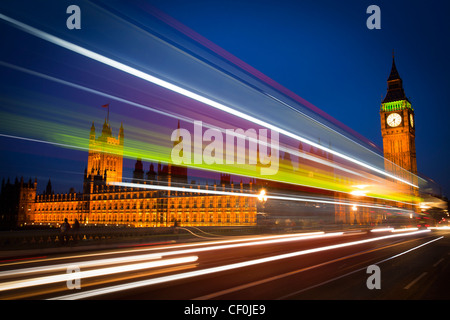 La sfocatura del traffico che attraversa Westminster Bridge che si affaccia il Palazzo del Parlamento e il Big Ben a Londra Foto Stock