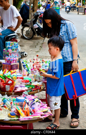 Una madre e figlio acquistare dolci dopo la scuola in Hoi An, Vietnam Foto Stock