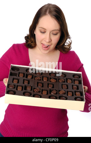 Donna indulgere in una grande scatola di cioccolatini e caramelle. Foto Stock