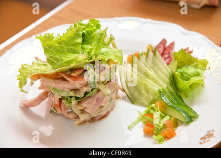 Insalata di diversi tipi di salsicce, cetrioli, peperoni, lattuga con panna acida salsa Foto Stock