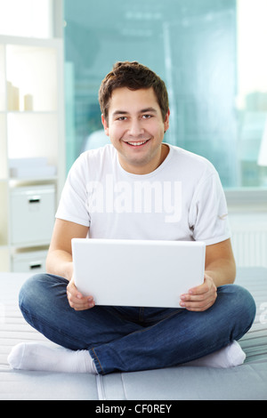 Felice ragazzo con laptop guardando la fotocamera e sorridente Foto Stock