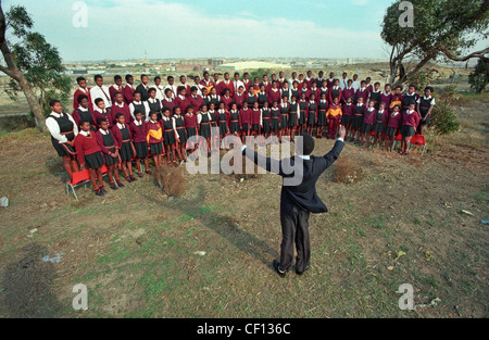 Il nero di scolari di cantare in un coro scolastico condotta dall'insegnante di musica in Port Elizabeth, Sud Africa. Foto Stock