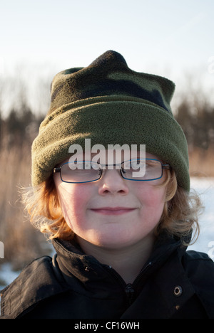 Un piccolo ragazzo con gli occhiali, in un cappello, sorridente. Foto Stock