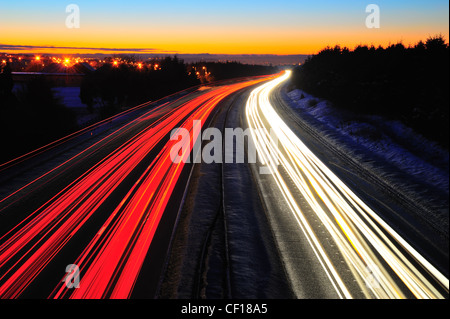 Traffico sentieri di luce sull'autostrada M8 in Scozia tra Glasgow e Edimburgo. Scattata di notte in inverno con neve sul terreno Foto Stock