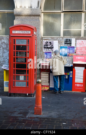 La gente di raccolta e libera lettura giornali cinesi da un edicola in Chinatown, Londra Foto Stock