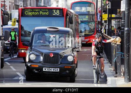 I ciclisti, i bus e i taxi in attesa ad un semaforo di Piccadilly. Foto Stock