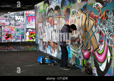 Un artista di graffiti a lavorare in una zona conosciuta come il sotto-croft sulla South Bank di Londra. Foto Stock