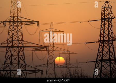 Elettricità tralicci stagliano al tramonto in Radley, Oxfordshire Foto Stock