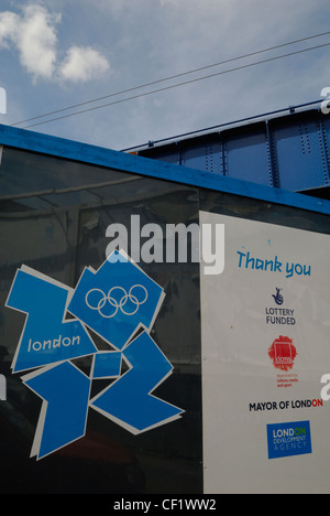 Il London 2012 Olympic logo visualizzato su spazi pubblicitari al di fuori dell'entrata del cantiere di costruzione del Villaggio Olimpico. Foto Stock