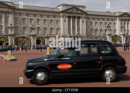 Un taxi a Londra passando la parte anteriore del Buckingham Palace. Foto Stock