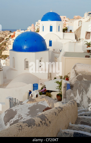 Una vista verso il basso un piccolo percorso di avvolgimento verso una serie di cupole blu greco chiese ortodosse nel villaggio di Santorini Foto Stock