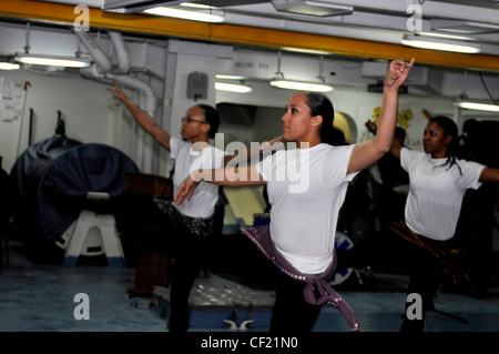 GOLFO ARABO (febbraio 25, 2012) Serviceman della nave terza Classe Teca Sneed, sinistra, Aviation Structural Mechanic (Equipment) 2a Classe Ana Wilson, assegnato al vettore Airborne Early Warning Squadron (VAW) 125, E Mate Fireman Davita Johnson, di destra, dell’elettricista, esegue una danza tradizionale africana durante una celebrazione del mese della storia afro-americana a bordo della portaerei di classe Nimitz USS Carl Vinson (CVN 70). Carl Vinson e Carrier Air Wing (CVW) 17 sono distribuiti nell'area di responsabilità della 5a flotta statunitense. Foto Stock