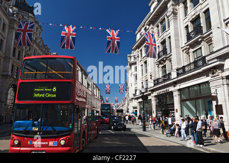 Red double decker bus e taxi viaggiano lungo Regent Street in rosso, bianco e blu bunting infilate attraverso la strada a c Foto Stock