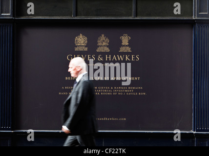 Un uomo a piedi passato Gieves & Hawkes, bespoke tailors in Savile Row. Foto Stock