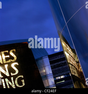 Il Wales Millennium Centre di notte. Aperto nel 2004, è un centro per le arti dello spettacolo si trova sulla baia di Cardiff waterfro Foto Stock