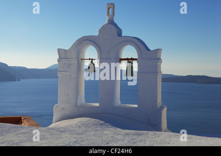 Una vista di una torre campanaria appollaiato sul tetto di una chiesa ortodossa greca nel villaggio di Oia Foto Stock