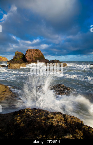 Onde che si infrangono contro gli affioramenti rocciosi vicino al porto di St Abbs. Foto Stock