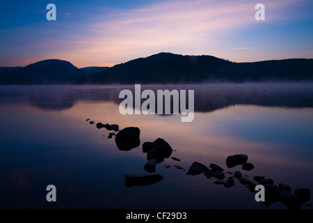 Parco Nazionale del Distretto dei Laghi. Alba a bassa Wray, guardando attraverso le acque ancora di Windermere, il lago più grande per essere trovato in en Foto Stock