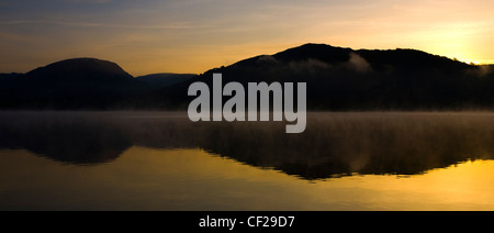 Parco Nazionale del Distretto dei Laghi. Alba a bassa Wray, guardando attraverso le acque ancora di Windermere, il lago più grande per essere trovato in en Foto Stock