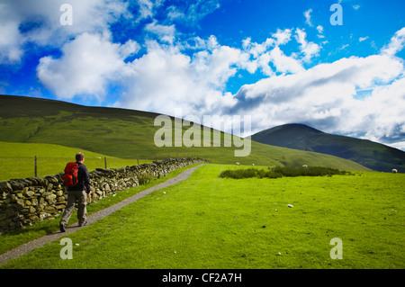 Il Parco nazionale del Lake District. Un escursionista in direzione inferiore e Lonscale Caldbeck comune su un tratto della Cumbria modo. Foto Stock
