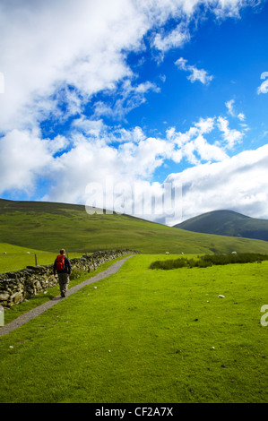 Il Parco nazionale del Lake District. Un escursionista in direzione inferiore e Lonscale Caldbeck comune su un tratto della Cumbria modo. Foto Stock