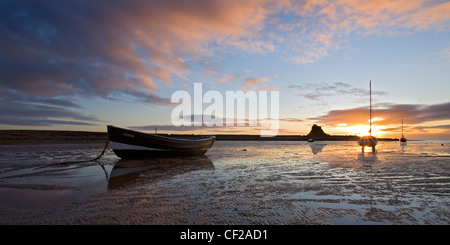 Alba sul Isola Santa castle e barche ormeggiate a bassa marea in Northumberland. Foto Stock