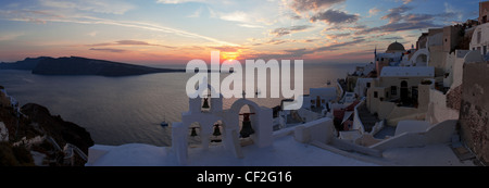 Una vista panoramica di una torre campanaria nel villaggio di Oia al tramonto Foto Stock