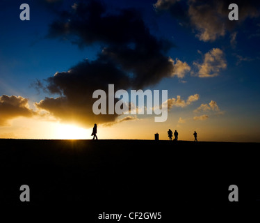 Sagome di persone che camminano al tramonto. Foto Stock