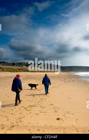 Un giovane a piedi il loro cane sul Praa Sands. Foto Stock