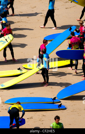 Persone in una scuola di surf su una spiaggia di Newquay. Foto Stock