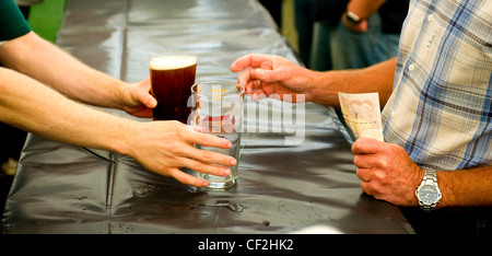 Un cliente che acquista una pinta di real ale presso il cerchio del Festival della birra in magazzino. Foto Stock