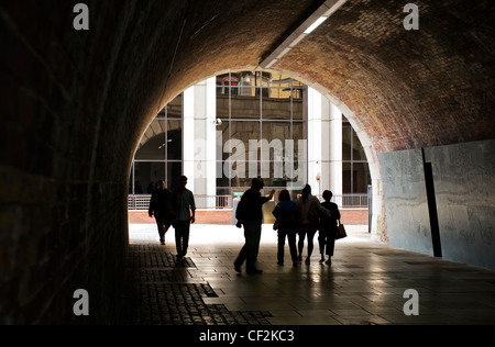 La silhouette di persone a piedi attraverso un tunnel sulla Thames Path a Londra. Foto Stock